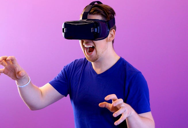 A young man wearing a 3D gaming visor and enjoying a Virtual Reality game